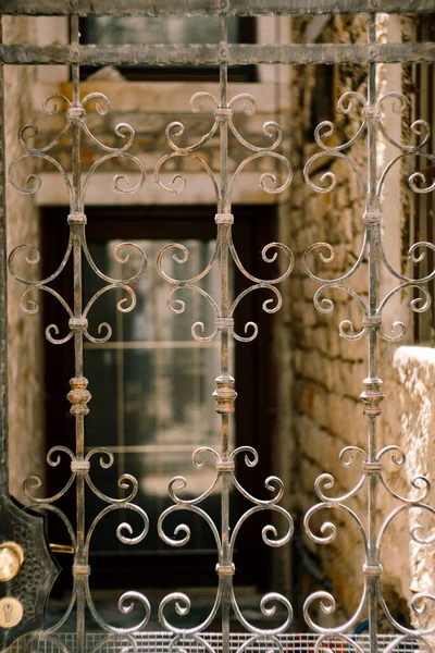 Puerta calada de metal forjado frente a un antiguo edificio de ladrillo —  Fotos de Stock