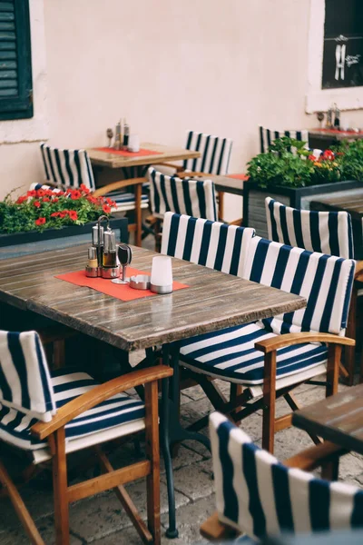 Sillas con capas a rayas en mesas de madera en un pequeño café acogedor — Foto de Stock