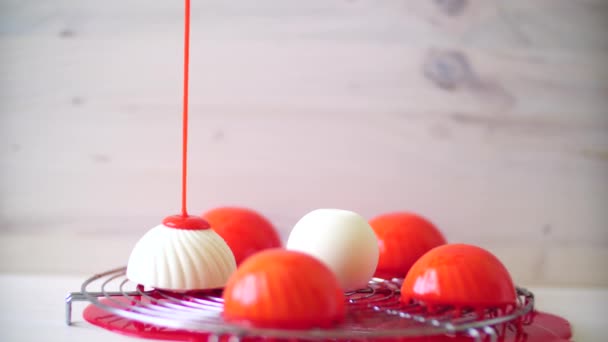 ペストリーシェフが赤い鏡の釉薬で白い個々のムースケーキを注ぐ — ストック動画