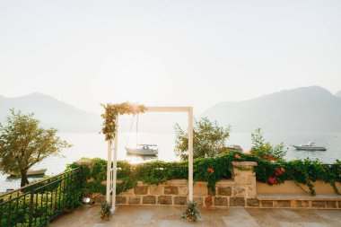 Gözlem güvertesinde çiçeklerle süslenmiş düğün kemeri deniz manzaralı yüzen yatlarla