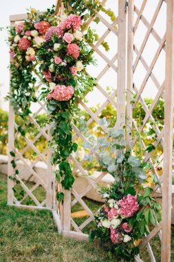 Katlanmış ahşap ekran çiçeklerle süslenmiş ve çimenlikte yeşillik dokuma tezgahları var.