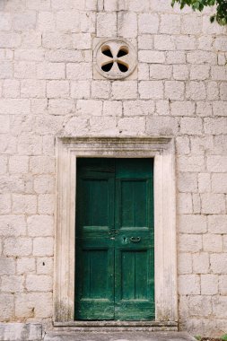 Binanın taş cephesinde çekmeli yeşil ahşap kapı.