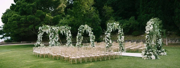 Fila de arcos de boda en un césped verde rodeado de sillas — Foto de Stock
