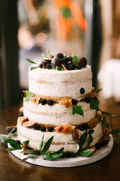 Casamento bolo de três camadas decorado com amoras, figos, ameixas e folhas verdes fica na mesa — Fotografia de Stock