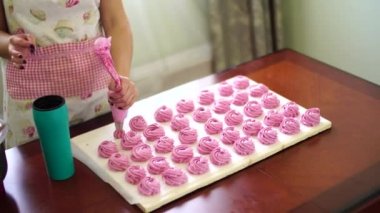 Dişi eller fırın kağıdına sıralanmış dut şekerlemeleri sıkıştırıyor.