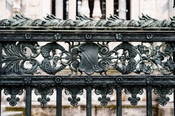 Antique wrought iron fence near the Duomo Cathedral in Milan with spikelets, shields, flowers and curls — Fotografia de Stock