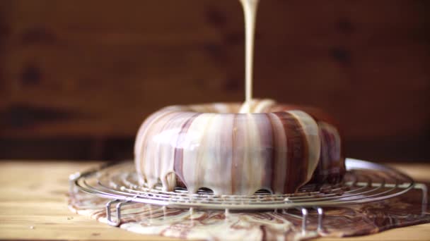 Pastry chef pours white and brown chocolate marble icing over mousse cake — Stock Video