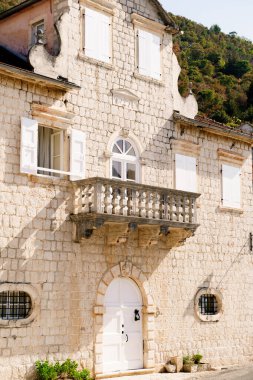 Kepenkleri ve balkonu olan taş bir binanın ön cephesi. Perast, Karadağ