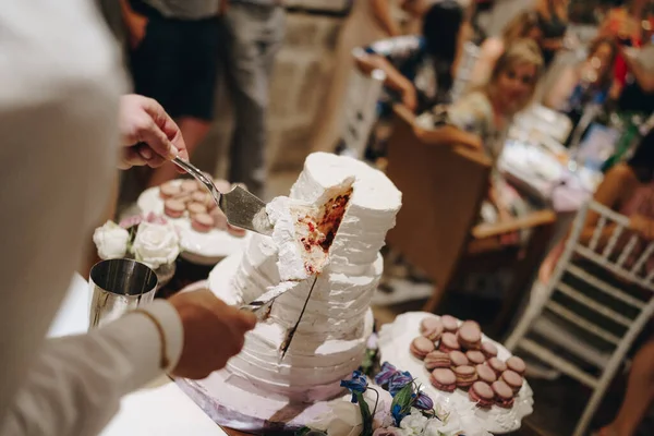 Man hands hold a piece of wedding cake on a knife and spatula — Stock Photo, Image