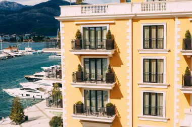 Porto tatil köyünde yatları olan iskelenin arka planında balkonları olan modern bir binanın ön cephesi.