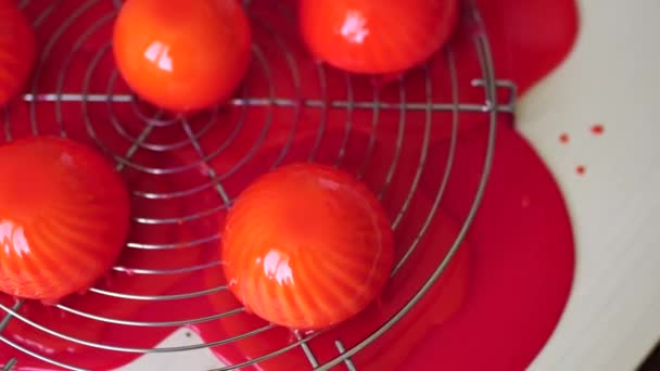 Round cakes covered with red mirror glaze lie on a metal stand — Stockvideo