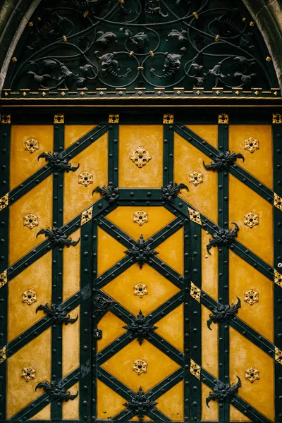 Yellow wooden door with wrought iron elements and floral decor — Fotografia de Stock