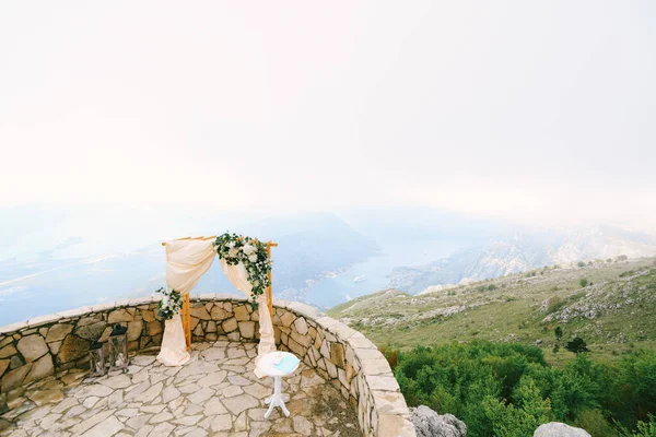 Bruidsboog staat naast de registratietafel op een observatiedek met uitzicht op de bergen — Stockfoto