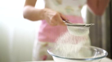 Metal elek içinden un çıkaran bir kadın.