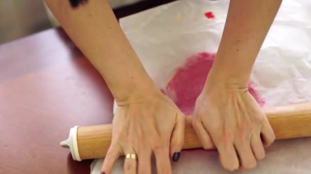 Woman rolls pink dough through baking paper with rolling pin — 图库视频影像