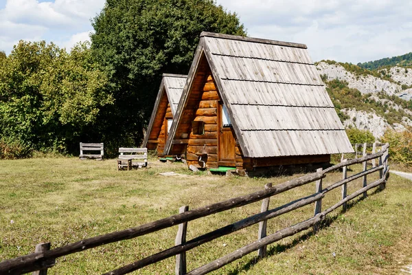 Háromszögletű faházak fából készült tetőkkel a kerítés mögött. Montenegró, észak — Stock Fotó