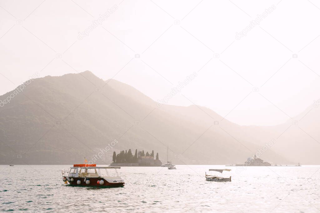 Pleasure boats sail past the islands of St. George and Gospa od Skrpjela in the Kotor Bay