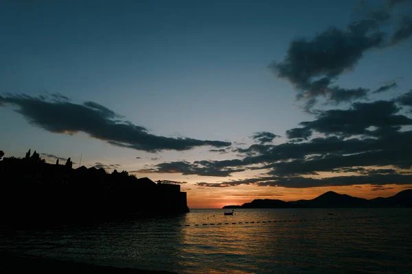 Sveti Stefan Island against the background of an orange sunset — стокове фото