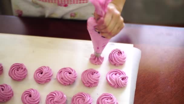 Female hands squeeze rows of berry marshmallows out of a pastry bag — Wideo stockowe