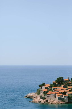 Sveti Stefan adasındaki ağaçlar arasında kırmızı çatıları olan evler