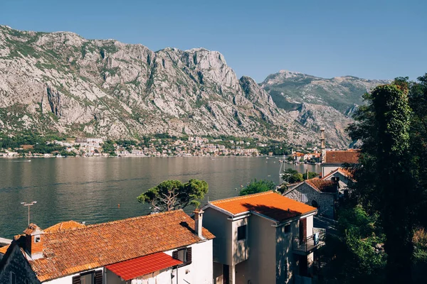 Kotor Körfezi 'nin parlak güneş ışığıyla manzarası evlerin çatıları üzerinde.