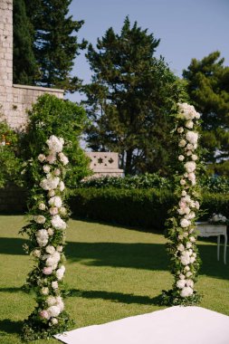 Düğünün yanındaki yeşil çimlerin üzerinde beyaz halı var. Gül desenli.