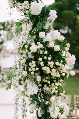 Güller, salkımlar ve yeşil yapraklarla süslenmiş hasır bir düğün kemeri parçası.