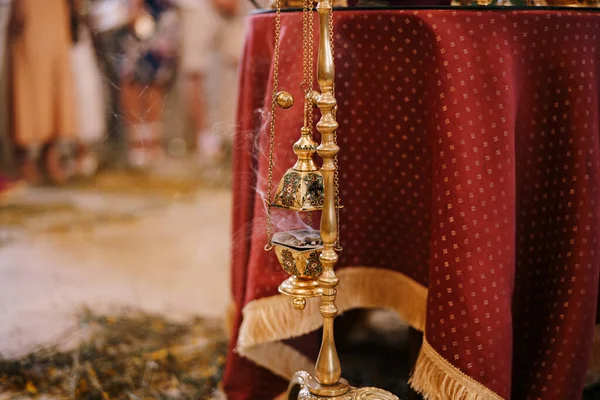 Kouření kadidlo visí na zlatém stojanu v chrámu u stolu s červeným ubrusem — Stock fotografie