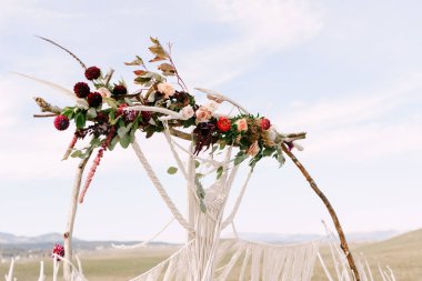 Parlak çiçekler ve beyaz makrome dantelle süslenmiş düğün kemeri