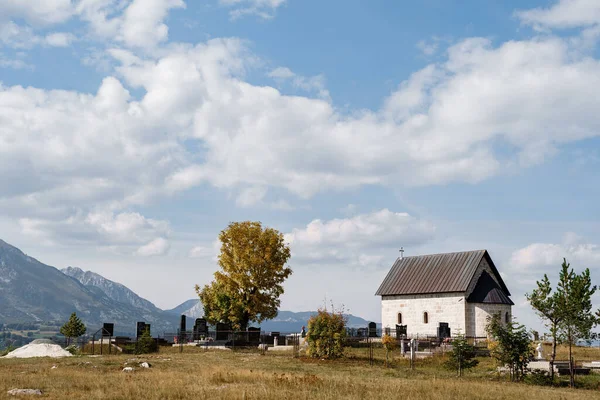 Old chapel near the cemetery in the field against the background of mountains — ストック写真