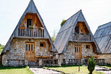 Tahta çatıları ve terasları olan üçgen taş evler. Karadağ, kuzey
