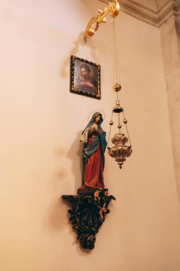 Simge, Bakire Meryem heykelinin üzerinde tapınağın duvarındaki oyma bir stantta asılı duruyor.