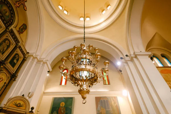 Gold chandelier hangs under the dome in the church on the background of icons — Stock Photo, Image