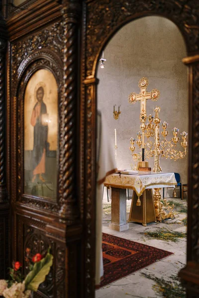 Candelero de oro sobre una mesa frente a una cruz en la Iglesia de San Sava en Tivat. Vista a través del arco — Foto de Stock