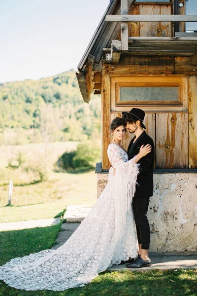 Groom hugs bride near the wall of a house. Side view Stock Photo