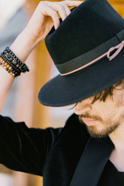 Kafasına siyah şapka takan genç bir adamın portresi.