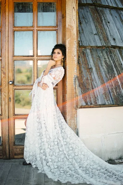 Νύφη με λευκό ψάθινο φόρεμα ακουμπισμένη στο πλαίσιο της πόρτας — Φωτογραφία Αρχείου