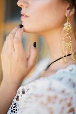 Genç bir kadın çenesine parmaklarıyla dokunuyor. Yakın plan.