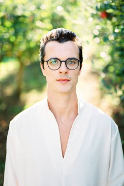 Beyaz gömlekli ve yeşil dallı bir adamın portresi.