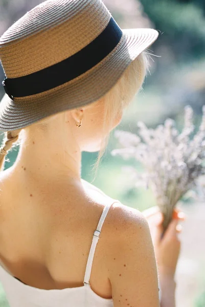 Elinde lavanta buketi olan hasır şapkalı bir kadın. Arka plan