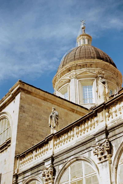 Stone statues on the balustrade of an ancient temple against the background of the dome Stock Image