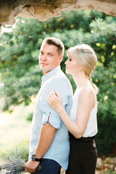 Woman hugs from behind a man on a green tree background — Stock Photo, Image