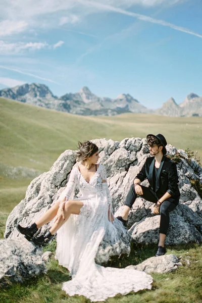 푸른 잔디 위의 돌 위에 앉아 있는 신부와 신랑 — 스톡 사진