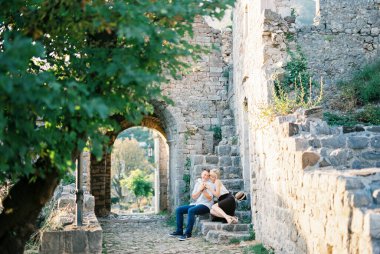 Kemerdeki taş bir şatonun merdivenlerinde oturan kucaklaşan çift.