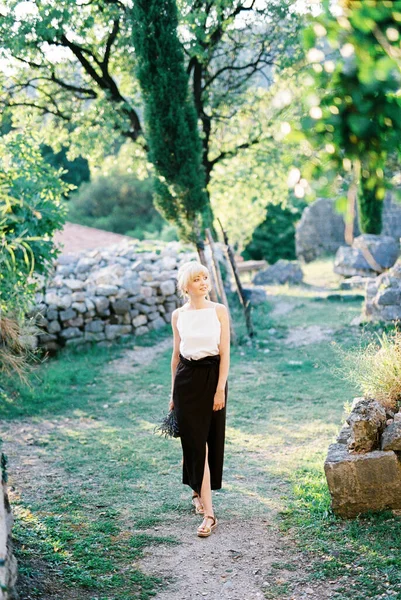 緑の庭の道を歩いてラベンダーの花束を持つ女性 — ストック写真