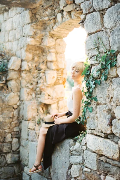 Mladá žena sedí na okně kamenné zdi starobylé budovy — Stock fotografie