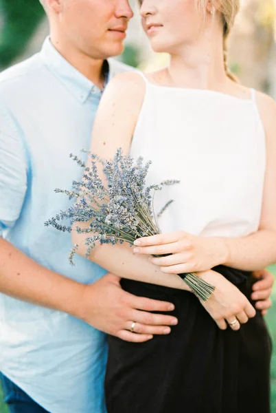 Der Mann umarmt eine Frau mit einem Lavendelstrauß. Porträt — Stockfoto