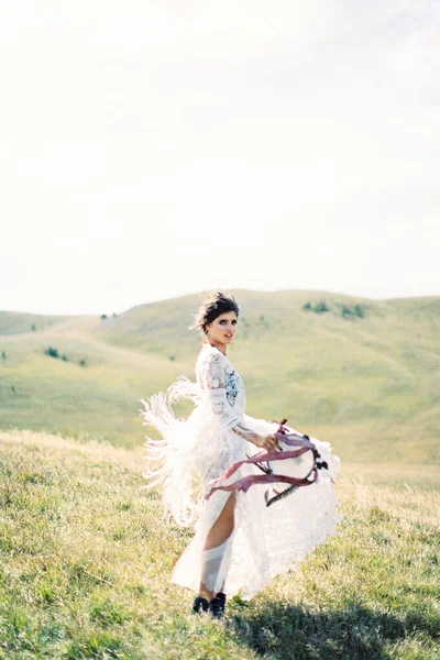 Gadis dalam gaun putih berdiri di lembah hijau dengan tamborin — Stok Foto