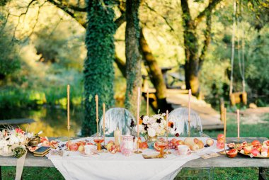 Bahçede meyve ve mumlarla dolu bir masa.