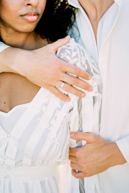 Adam bir kadını omuzlarından kucaklıyor. Yakın plan.